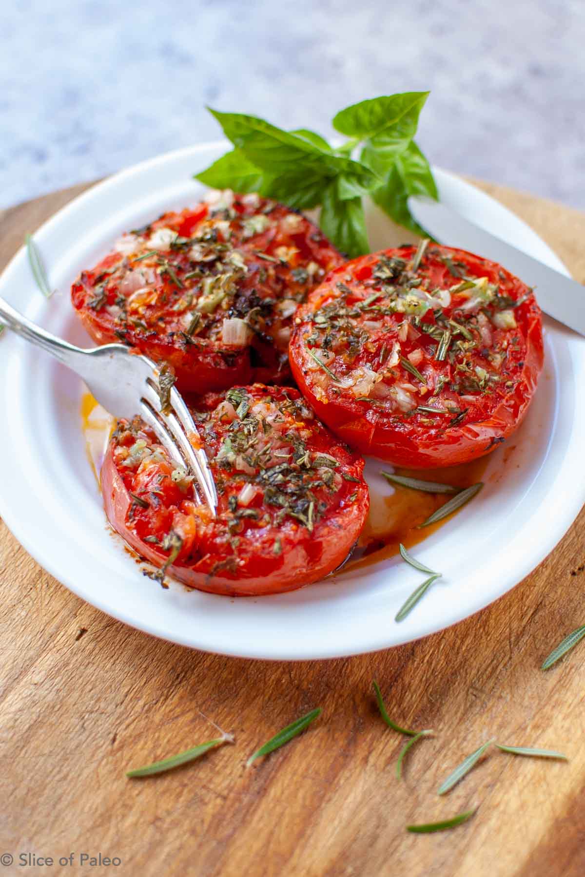 Provencal Tomatoes on a white plate with fork and knife